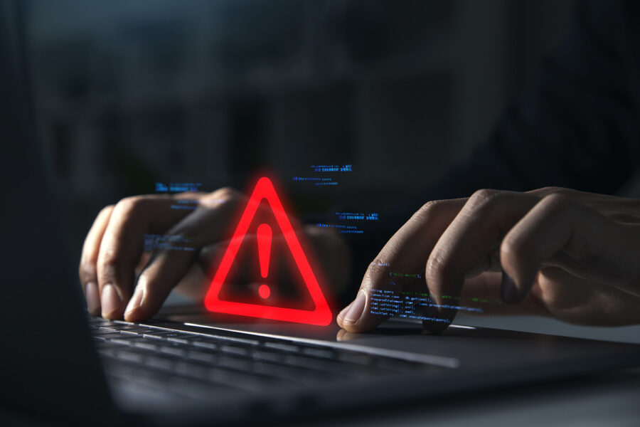 Hand of businessman using laptop with caution warning sign for notification error and maintenance concept.